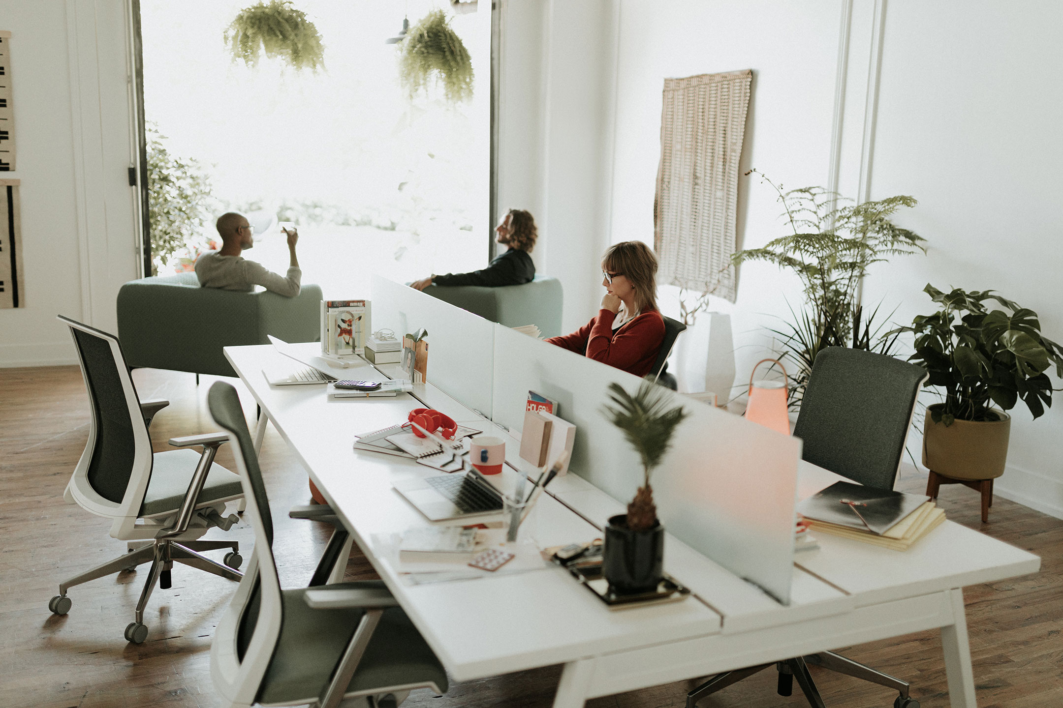 Haworth Intuity Workspace divider that are translucent in office space with employee working at desk and employees collaborating in lounge area next to window