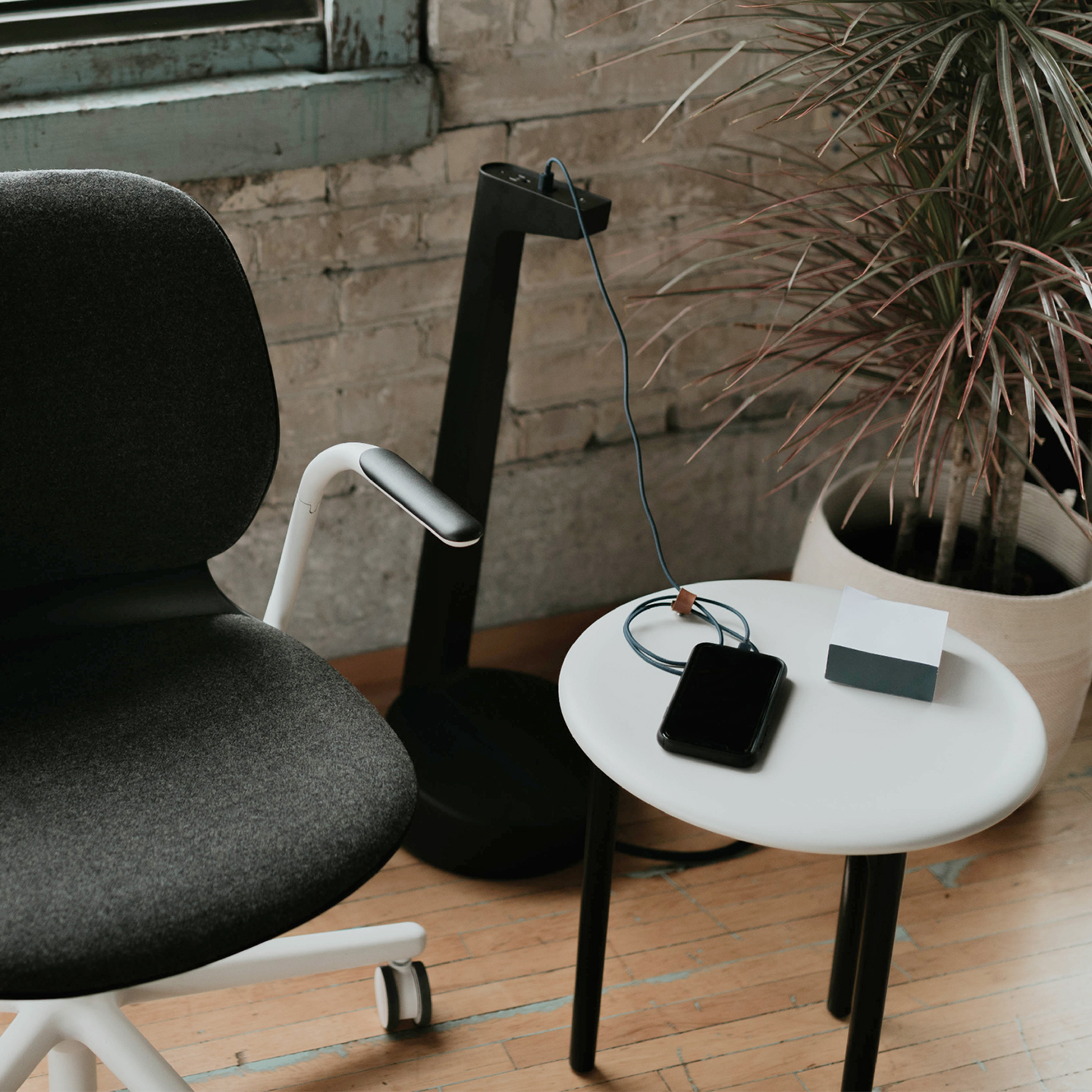 Haworth Collaborative Power Accessories tower with usb and wall port next to small table and chair used to charge a phone