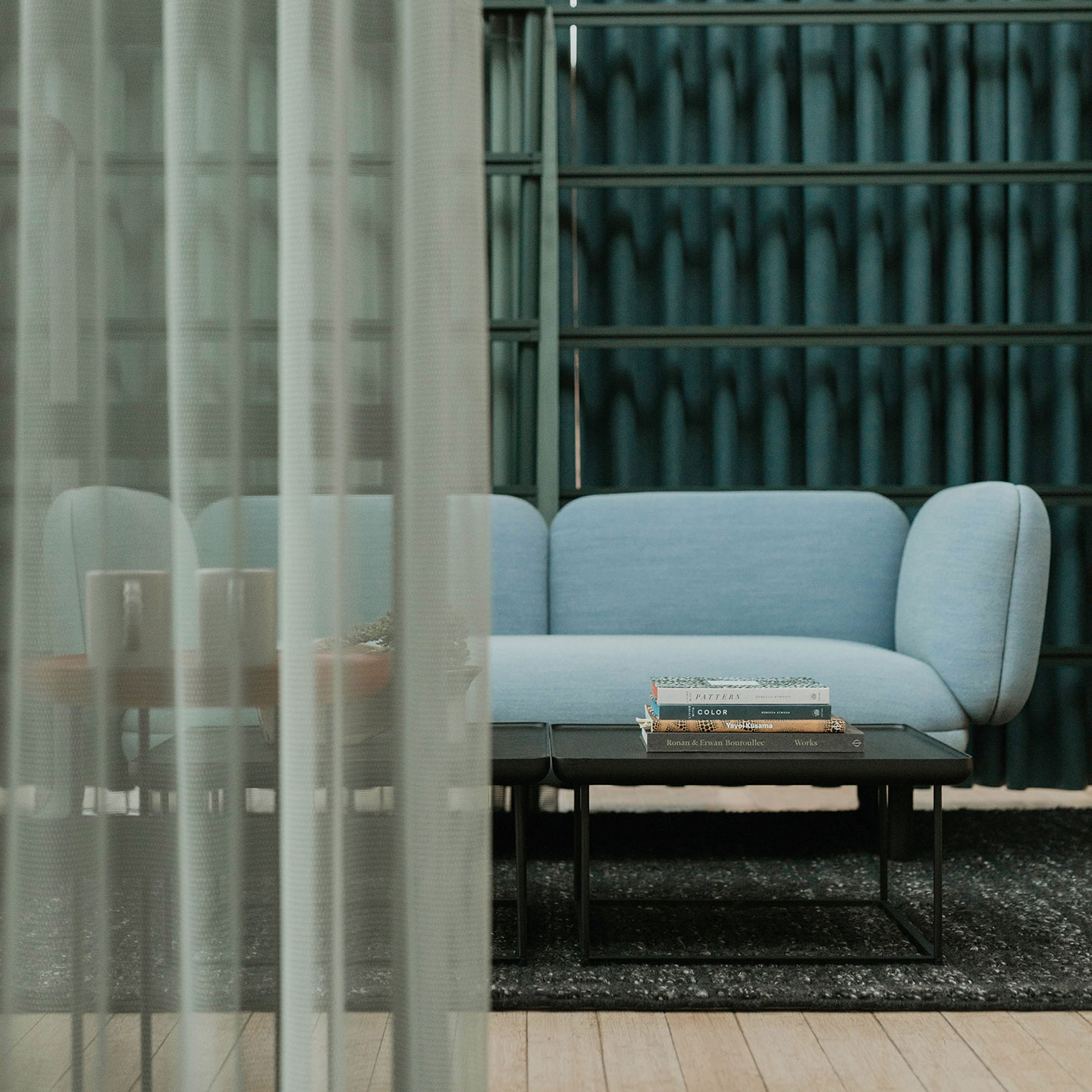Haworth Mangas Natural Rug in black color and sqaure pattern in blue couch and black table covered by green privacy booth