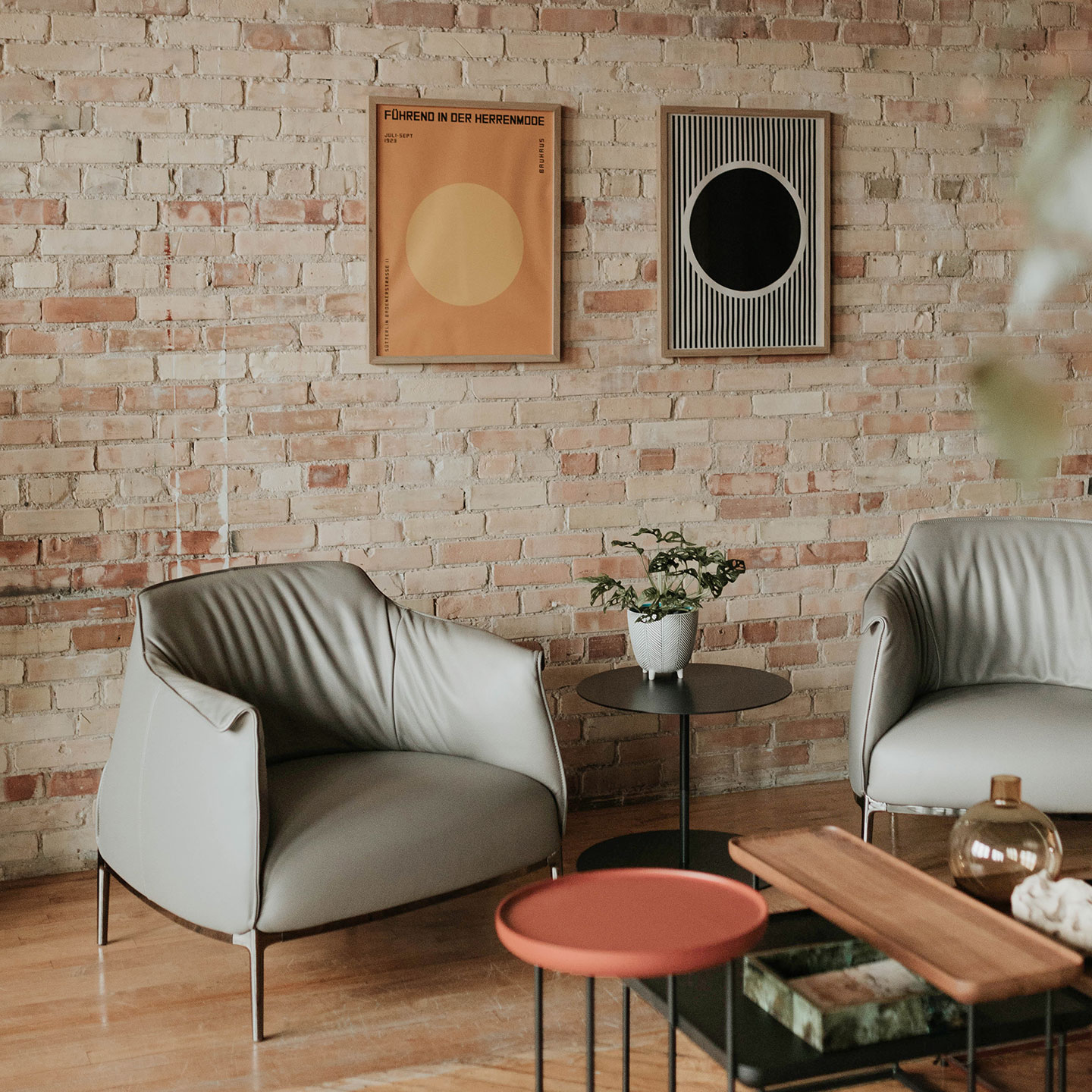Haworth gong table with circular base and top in black in living room with brick walls and 2 chairs